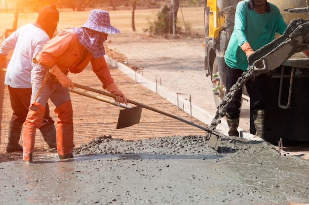 Arbeiders die beton gieten met een vrachtwagen van de cementmixer