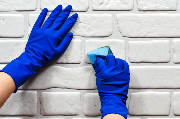 Arbeidershanden in rubberen beschermende handschoenen met een doek die het oppervlak van een tafel of muur in een kamer badkamer keuken afveegt Het concept van netheid