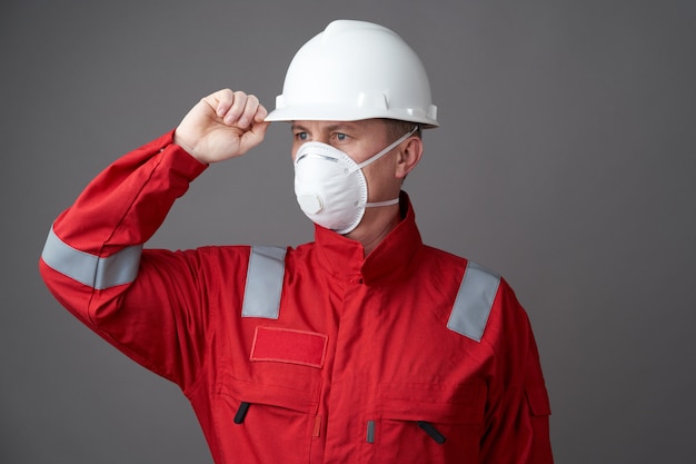 Foto arbeidersmens die hygiënisch masker, algemene en beschermende bouwvakker draagt