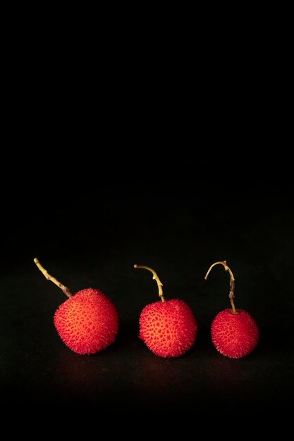 Arbutus, the fruit of the strawberry tree, with a black background and with copy space.