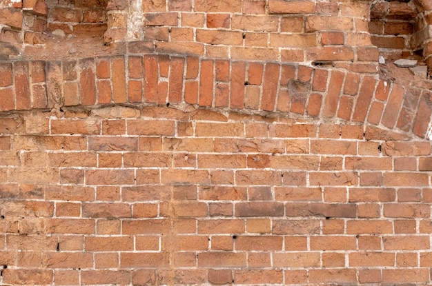 Arch in ancient brickwork on abandoned old house red brick wall fragment closeup