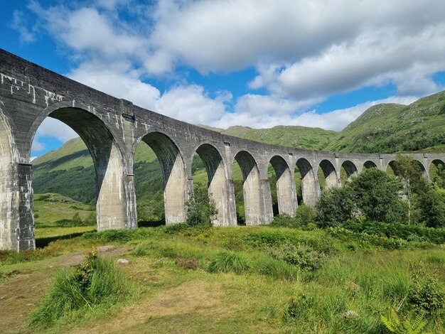 Arch bridge on field against sky