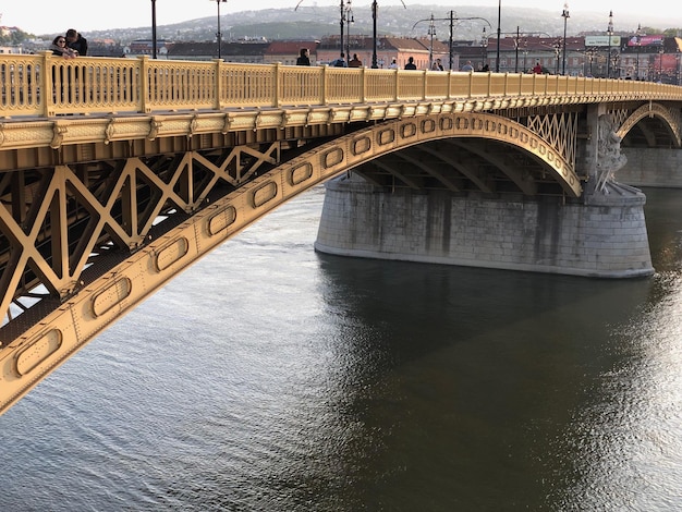 Фото Арковый мост через реку в городе напротив неба
