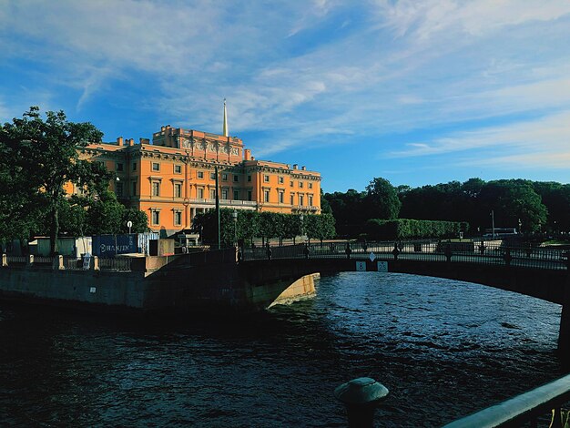 arch bridge over river by buildings against sky