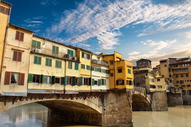 Arch bridge over river by buildings against sky