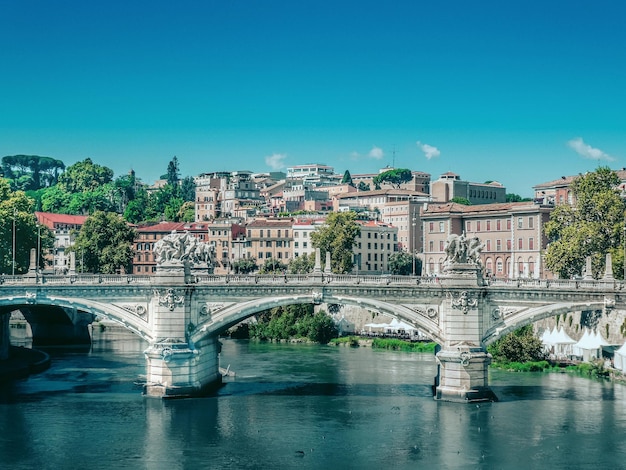 Arch bridge over river in city against blue sky