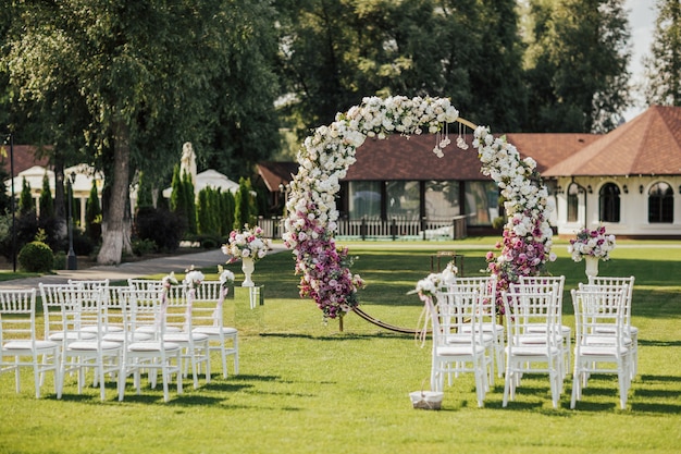 Arch, decorated with pink and white flowers standing in the park