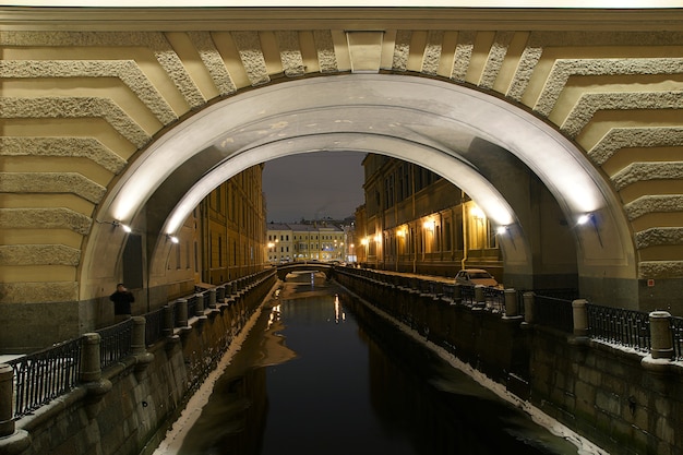 Arch over the river with reflective lanterns and buildings in a winter evening