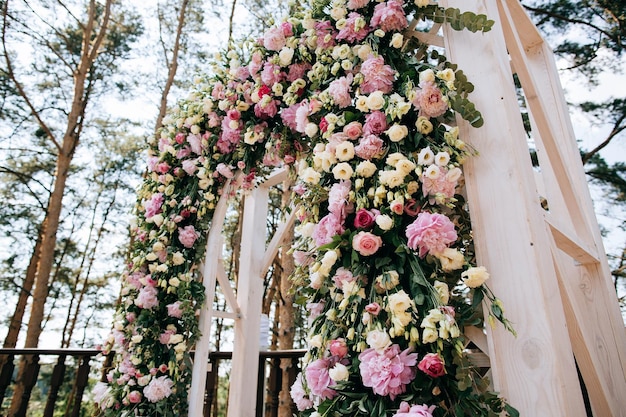 Арка для свадебной церемонии, украшенная живыми цветами в сосновом лесуx9