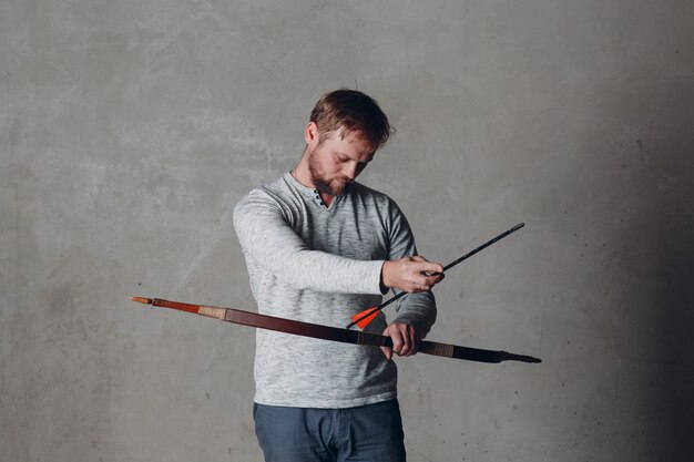 Archer bearded man with classic bow and arrow.