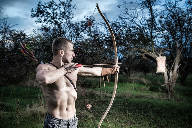 Photo archery. a young man aiming a bow at a target