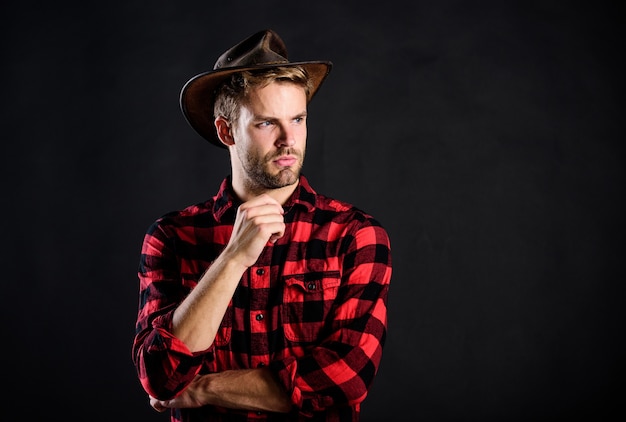 Archetypal image of Americans abroad. Cowboy life came to be highly romanticized. Man unshaven cowboy black background. Masculinity and brutality concept. Adopt cowboy mannerisms as a fashion pose.