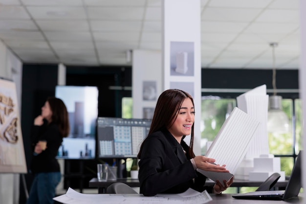 Architect bespreekt het bouwen van een 3D-geprint model op videocall in het architectenbureau. Aziatische werknemer praat over CAD-ontwerp op videoconferentie, online presentatie van ingenieurs, 3D-blauwdruk.