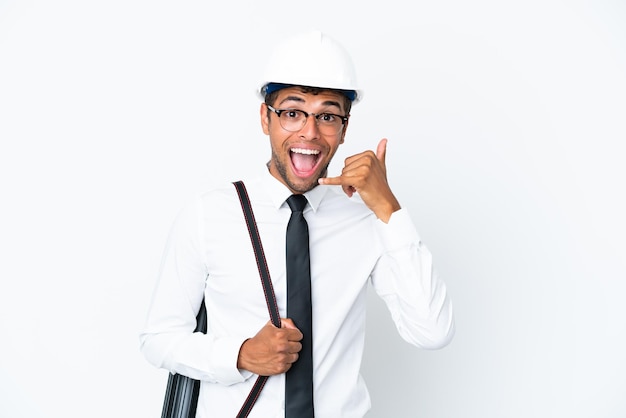 Architect braziliaanse man met helm en met blauwdrukken die een telefoongebaar maken. Bel me terug teken