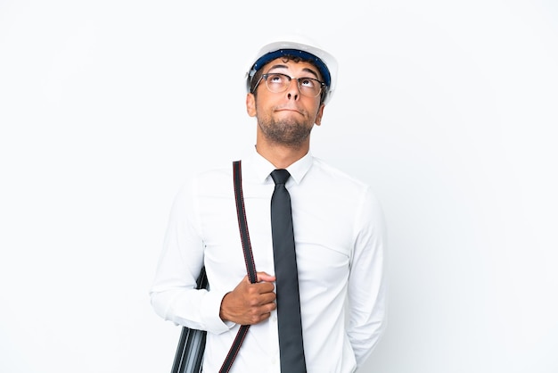 Architect brazilian man with helmet and holding blueprints and looking up