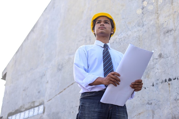 Architect builder with yellow helmet studying layout plan of the rooms serious civil engineer worki