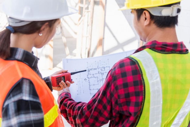 Photo architect and client discussing the plan with blueprint of the building at construction site. asian engineer foreman worker man and woman working talking on drawing paper to checking project