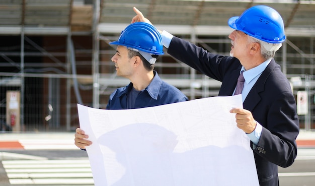 architect developers reviewing building plans at construction site