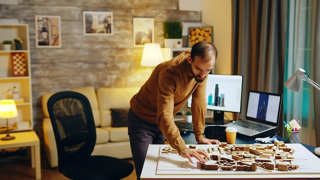 Architect die 's nachts in zijn kantoor aan huis werkt aan een stadsontwikkelingsproject. koffie drinken.