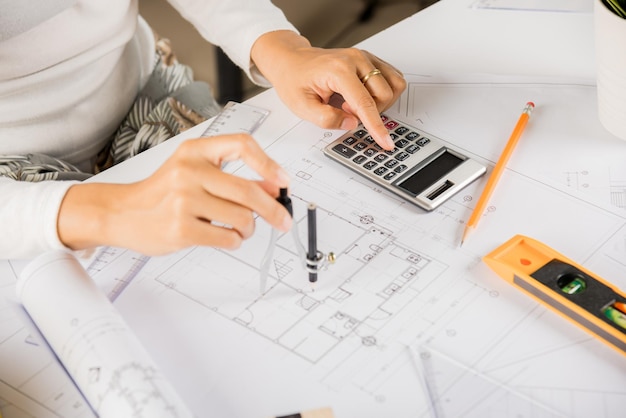 Architect drawing with divider compass on house plan blueprint paper