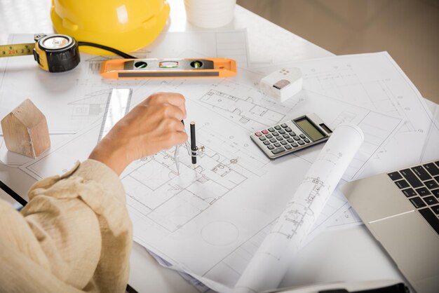 Architect drawing with divider compass on house plan blueprint paper