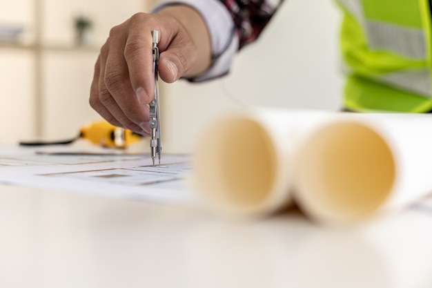 Architect engineer using compasses to write on the blueprints they have designed, he is checking and revising the drawings before submitting the work to the customers. Design and interior design ideas