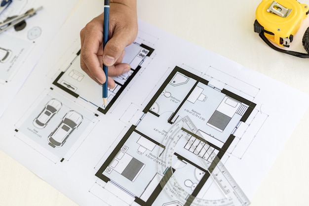 設計した設計図に鉛筆を使って書く建築技師は、顧客に作品を送る前に、図面をチェックして修正しています。デザインとインテリアデザインのアイデア。