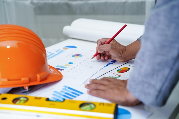 Photo architect or engineer working project accounting with graph and construction helmet in office construction account concept