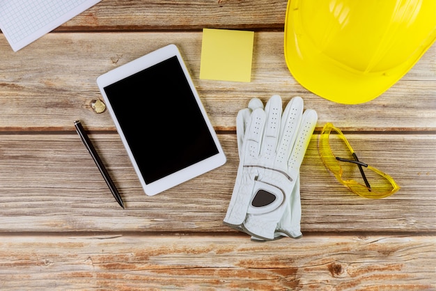 Architect engineer workplace standard construction safety equipment on gloves yellow helmet and tablet pc