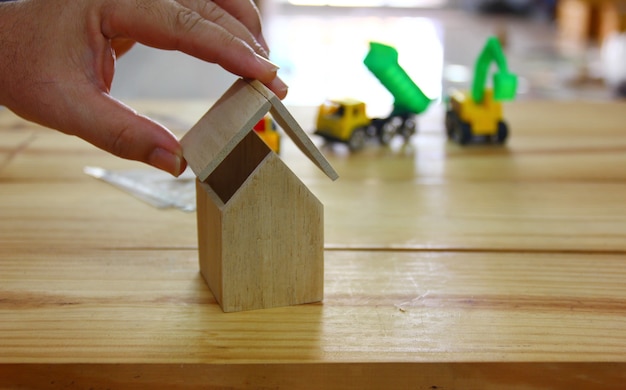 Architect or hame desinger is making the modle for presentation\
the owner.hand doing wood home and checking the scale with\
construction machine .