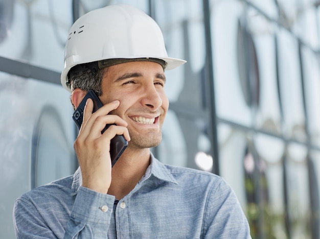 Architect in a hard hat speaks on a smartphone