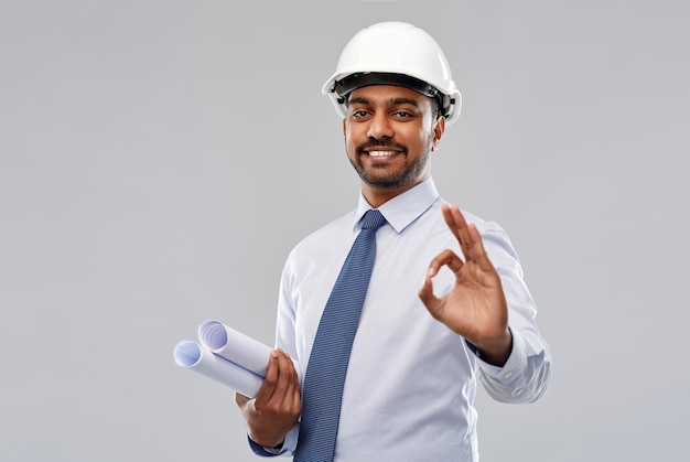 Photo architect in helmet with blueprints showing ok