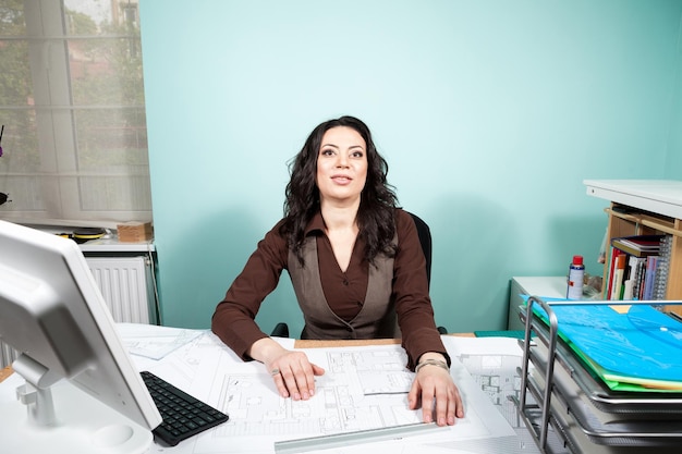 Architect at her working space with blueprints in front of her. Working on new projects. Architecture and design