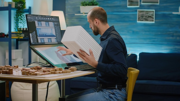 Architect holding maquette and analyzing building model for architectural development. Man looking at object for construction layout and to design blueprint plan. Modern architecture