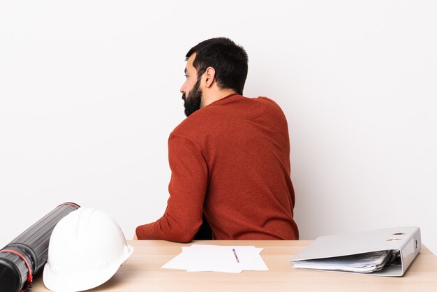 Architect man aan een tafel met plannen en helm