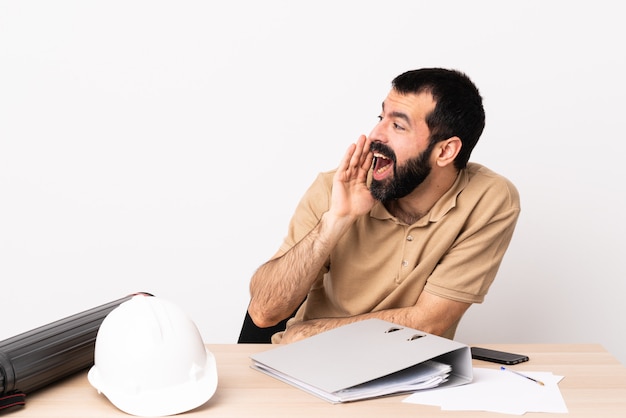 Architect man aan een tafel met plannen en helm