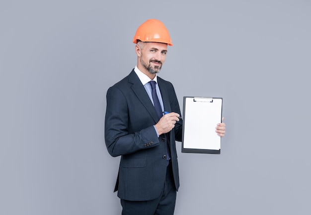 Architect man in businesslike suit and hardhat showing clipboard copy space planning