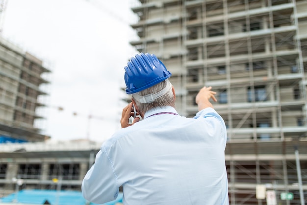 携帯電話で話していると建設現場に彼の指を指している建築家マネージャー