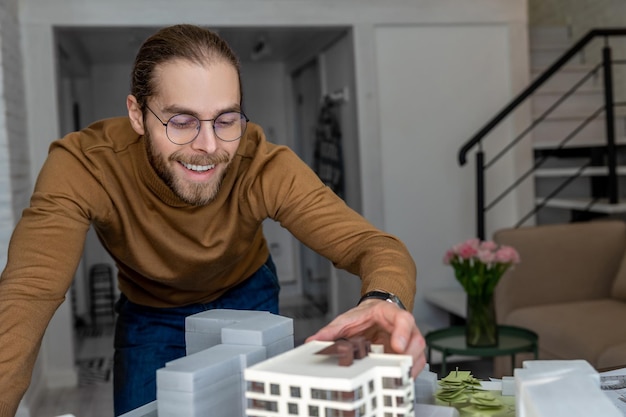 Architect met een bril die in het kantoor werkt bij de oprichting van een nieuw wooncomplex en de inrichting van gebouwen ontwerpt