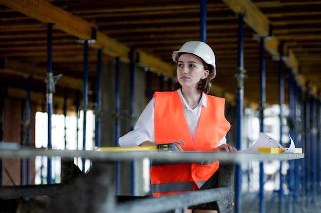 Architect of ingenieur aan het werk, browsen bouwproject binnen van bouwplaats met blauwdrukplan. vrouw bouwingenieurs of architecten werkende mensen.