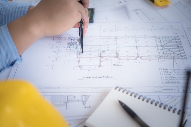 Photo architect or planner working on drawings for construction plans at a table