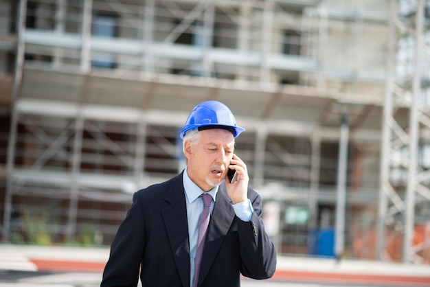 Photo architect talking on the phone outdoors in front of a construction site