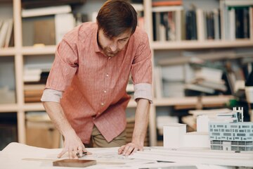 Architect with blueprints and layout design project at Bureau of  Architecture | Premium Photo