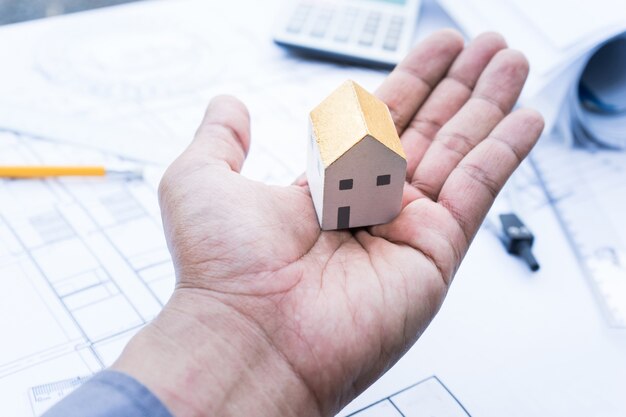 Architect with small house model on hand and plan design