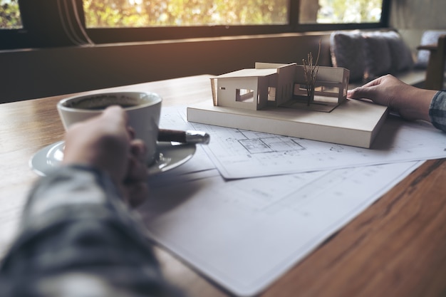 An architect working on an architecture model with shop drawing paper while drinking coffe