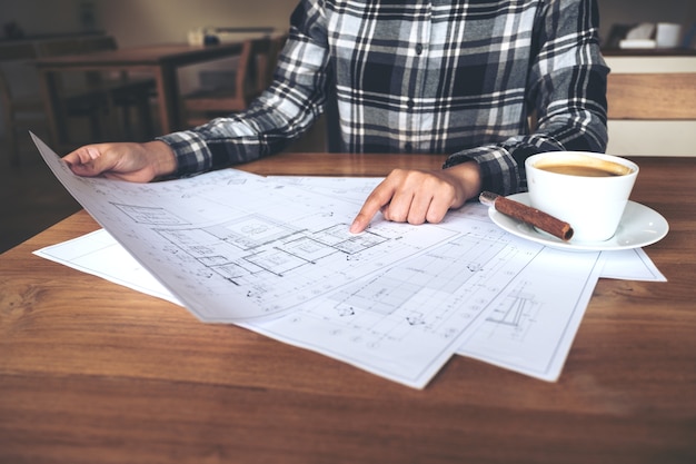 An architect working and pointing at shop drawing paper on table
