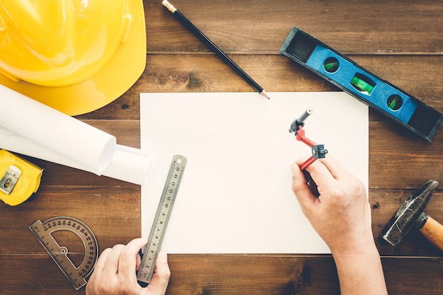 Architect working with construction tools and helmet safety on wooden background