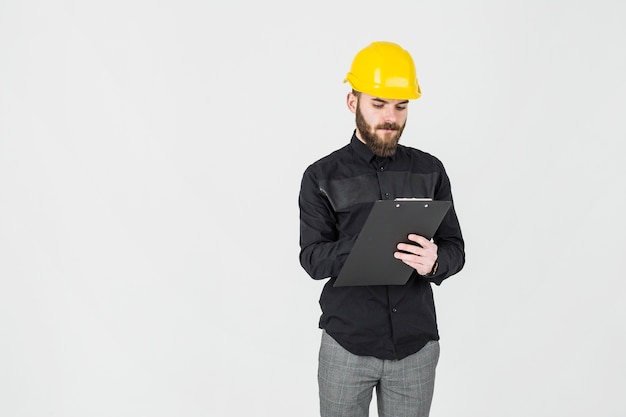 Architect writing on clipboard standing against white background