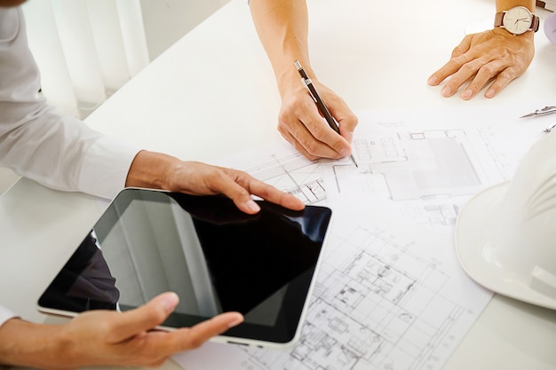 Architects engineer discussing at the table with blueprint - Closeup on hands and project print. 