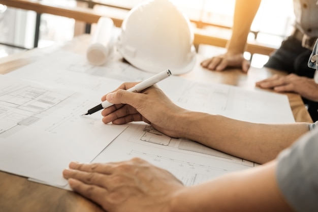 Photo architects engineer discussing at the table with blueprint - closeup on hands and project print